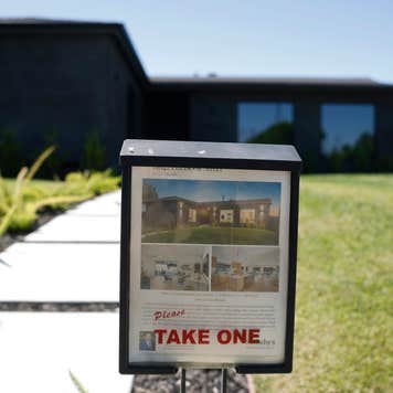 A "Pleast take one" sign in front of a for-sale property.
