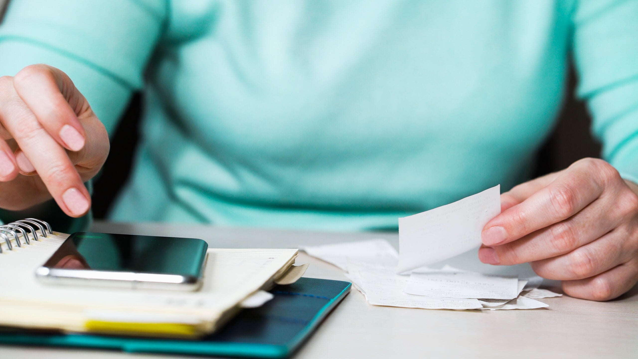 Close up of a woman holding receipts and using a calculator