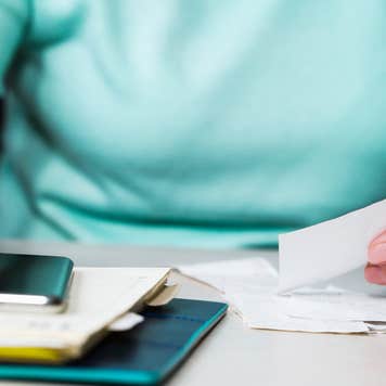 Close up of a woman holding receipts and using a calculator