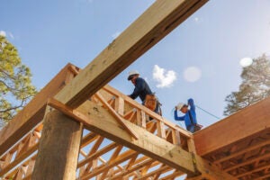 A cosntruction worker stands on the top of an under-construction structure