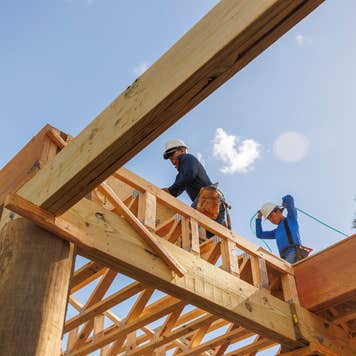 A cosntruction worker stands on the top of an under-construction structure