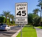 cars passing by a speeding limit sign