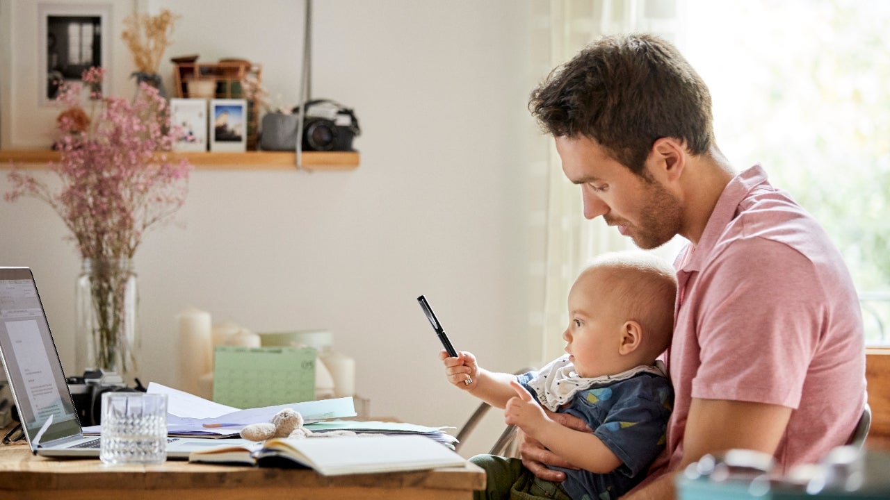 Father holding his baby child while working on financial documents