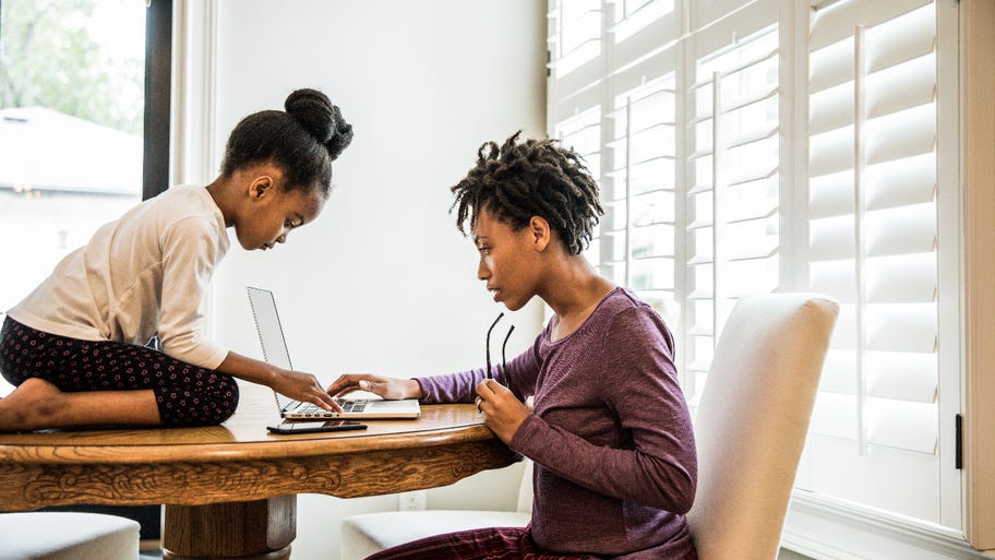 Mother, daughter bent over laptop and calculator