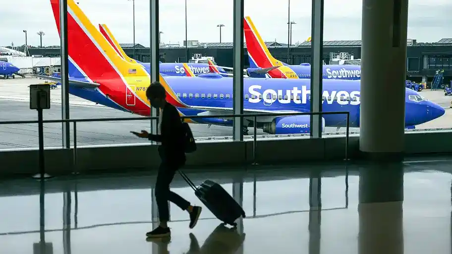 A traveler walks past a Southwest Airlines airplane as it taxies from a gate